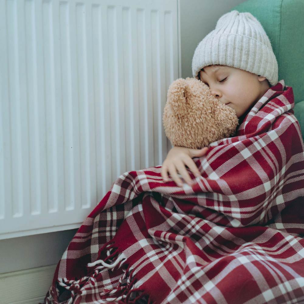 Boy in fuel poverty by radiator